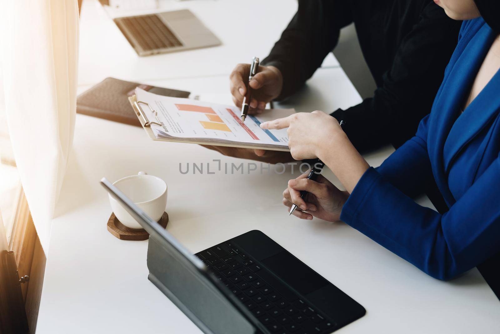 Teamwork concept, consultation, male economist holding pen pointing to budget, finance and investment documents, discussing and planning finances with female advisors in conference room. by Manastrong