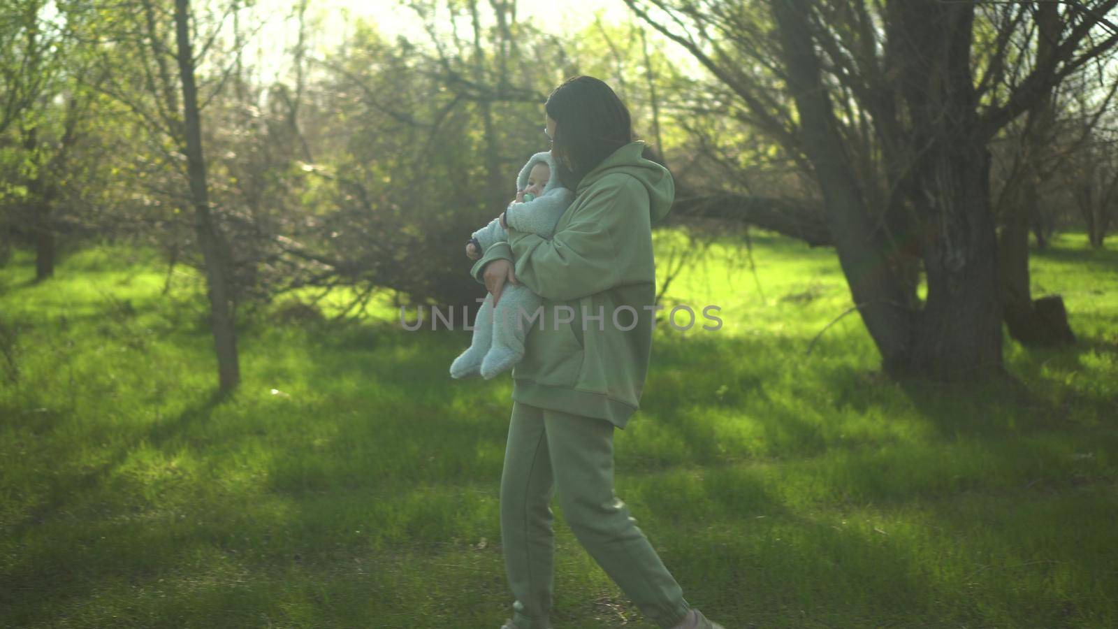 A young mother walks with a baby in nature. A girl with glasses holds a child in her arms. 4k