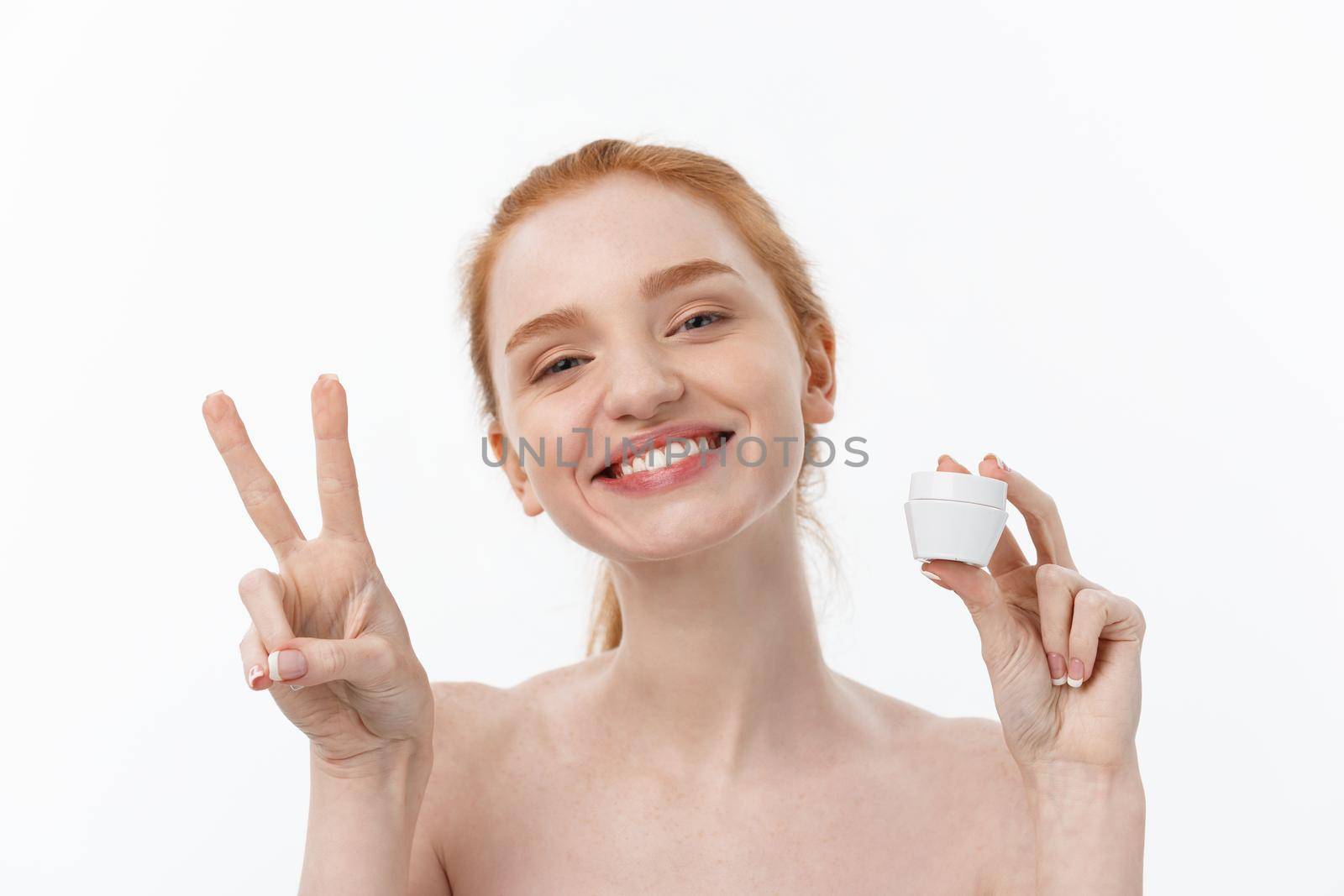 portrait of beautiful woman smiling while taking some facial cream isolated on white background with copy space