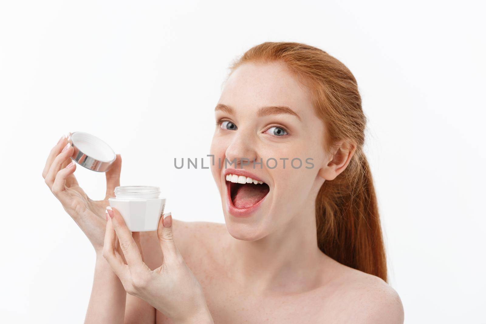 portrait of beautiful woman smiling while taking some facial cream isolated on white background with copy space