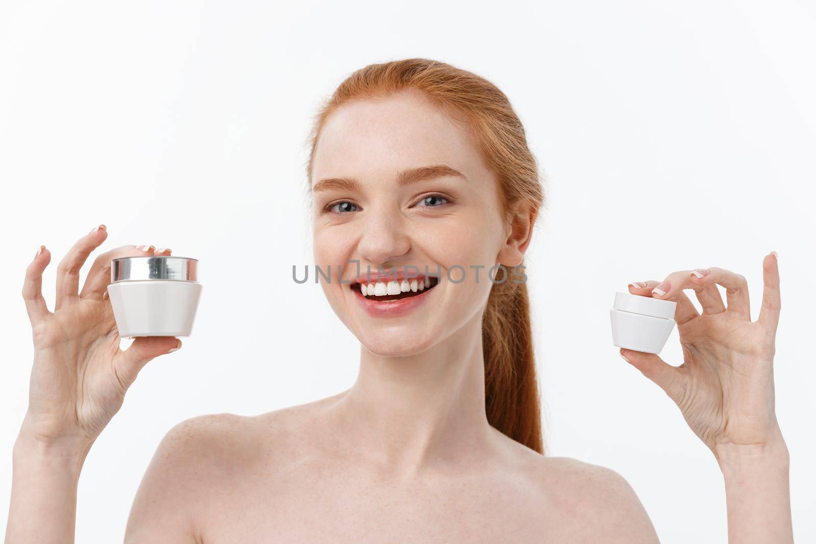 portrait of beautiful woman smiling while taking some facial cream isolated on white background with copy space