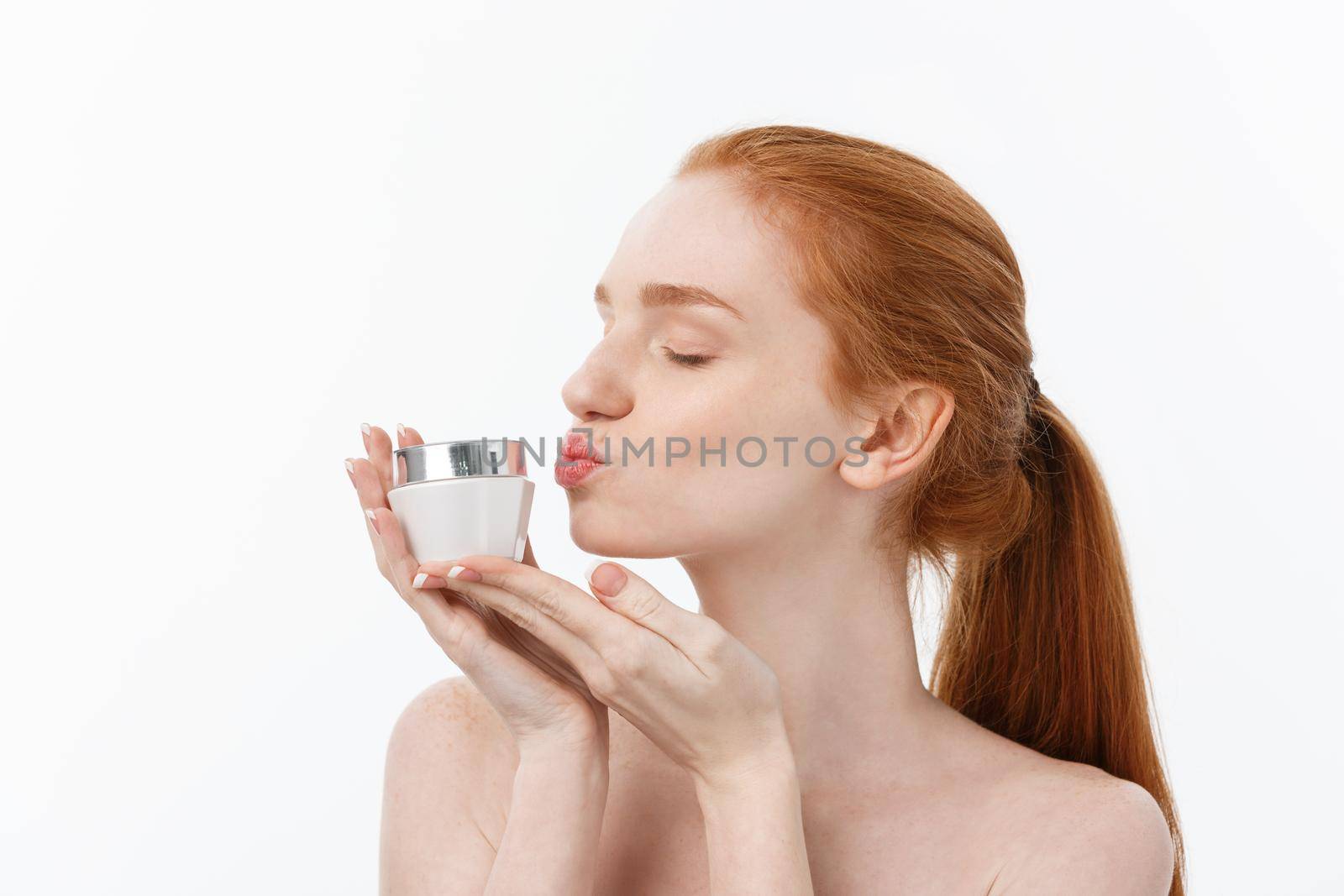 portrait of beautiful woman smiling while taking some facial cream isolated on white background with copy space