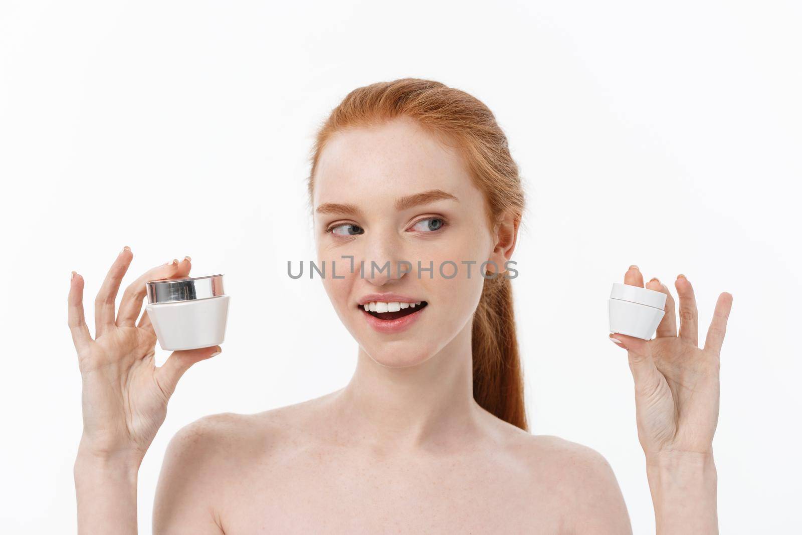 portrait of beautiful woman smiling while taking some facial cream isolated on white background with copy space