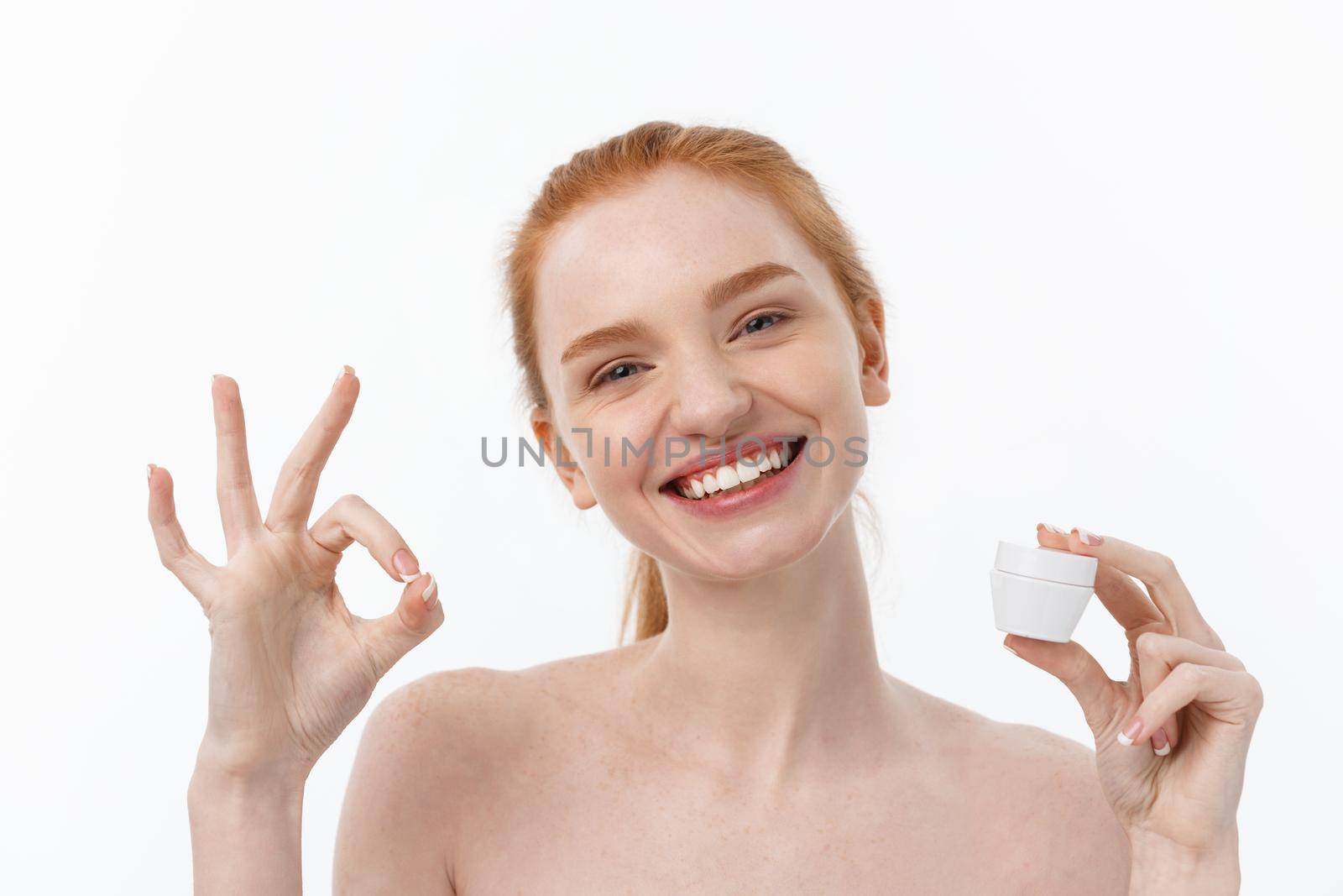 portrait of beautiful woman smiling while taking some facial cream isolated on white background with copy space