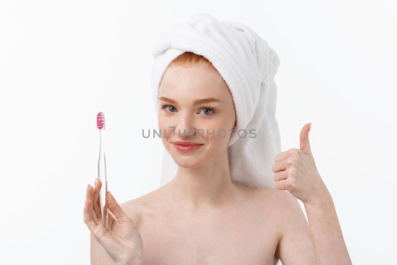 Portrait of young woman with toothbrush on grey background