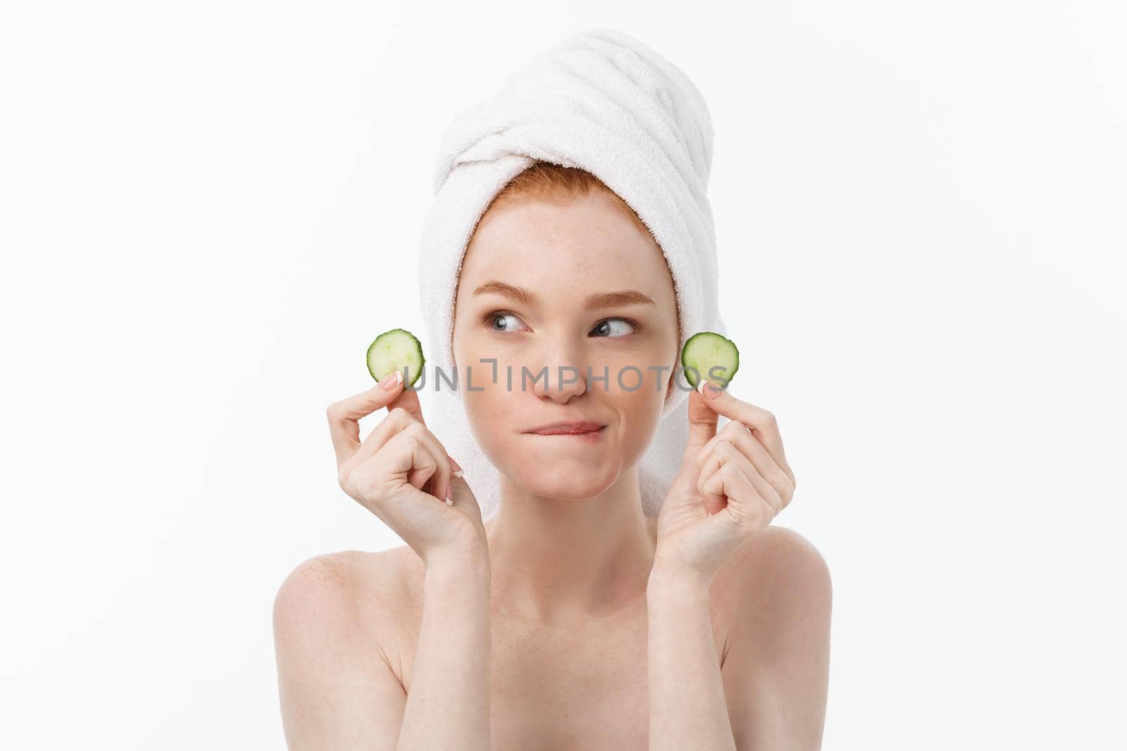 Attractive Young Woman with beautiful clean skin. White mask and cucumbers. Beauty treatments and cosmetology spa therapy. White background.