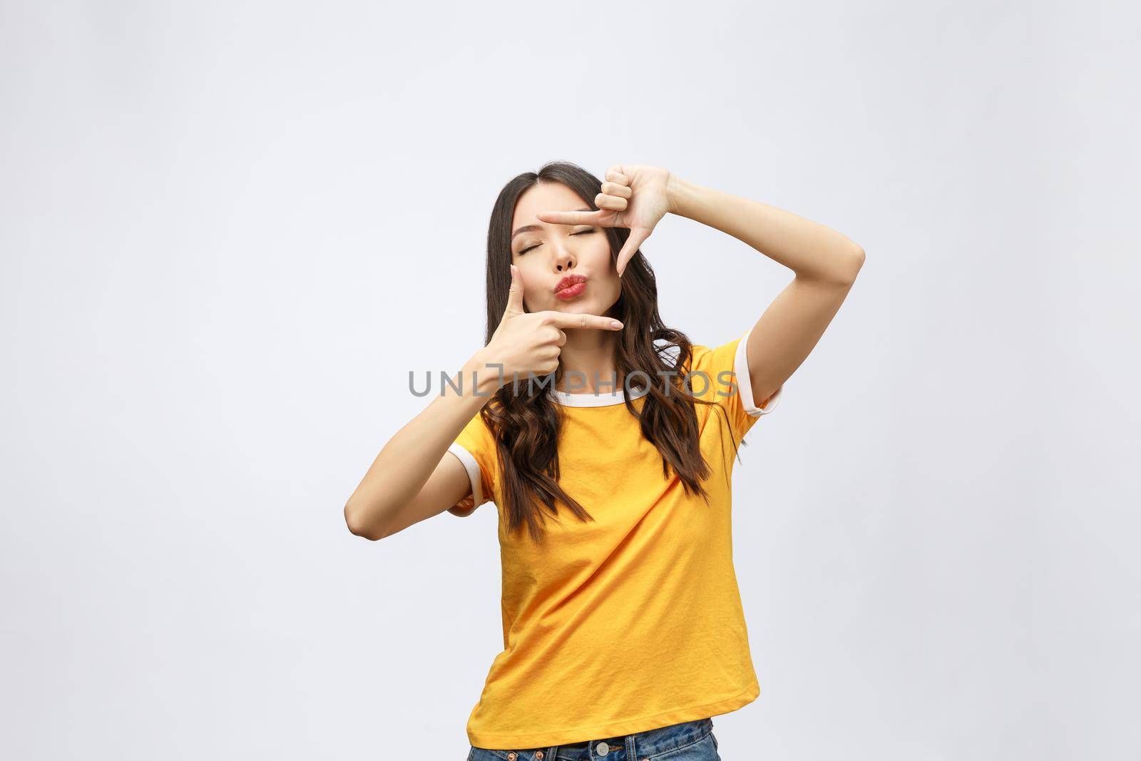young asian woman hands making frame gesture on grey background.