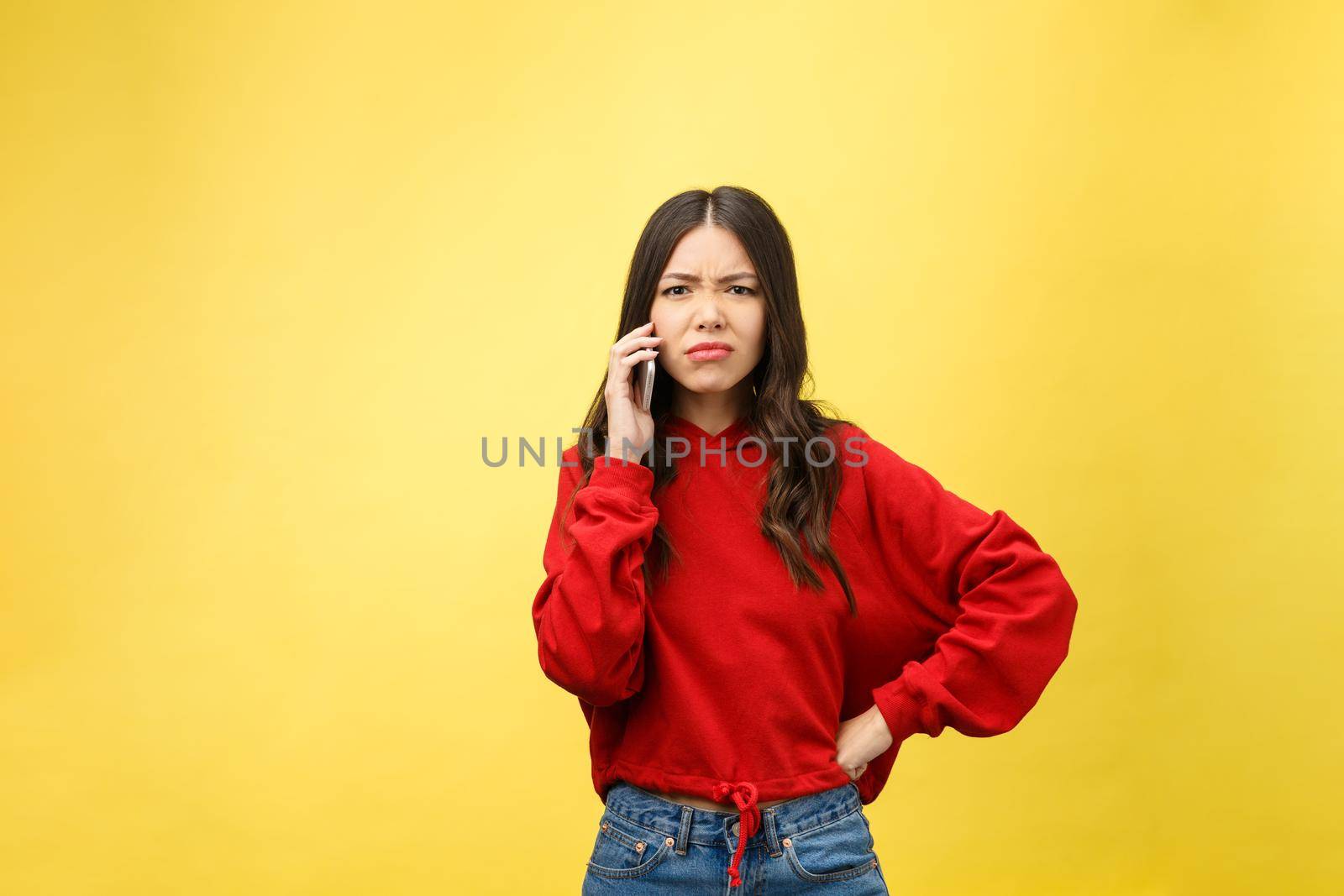 Portrait angry young asian woman disappoint at mobile phone while standing over yellow background by Benzoix