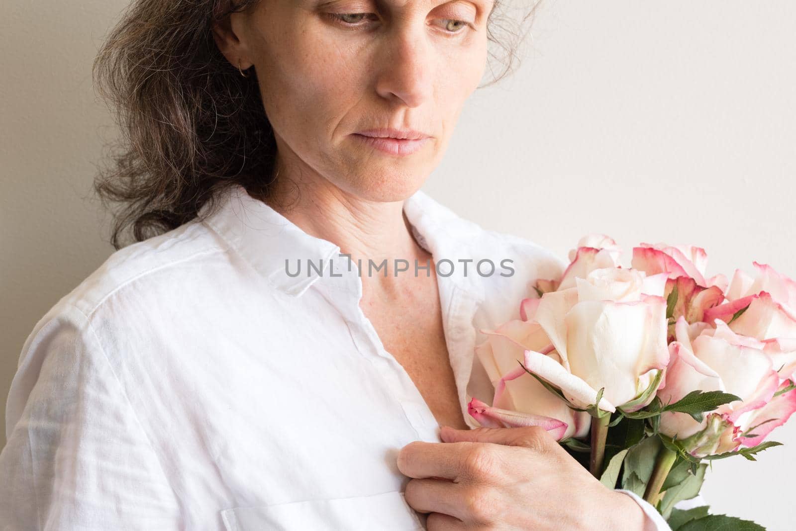 Middle aged woman holding roses and looking pensive (cropped)