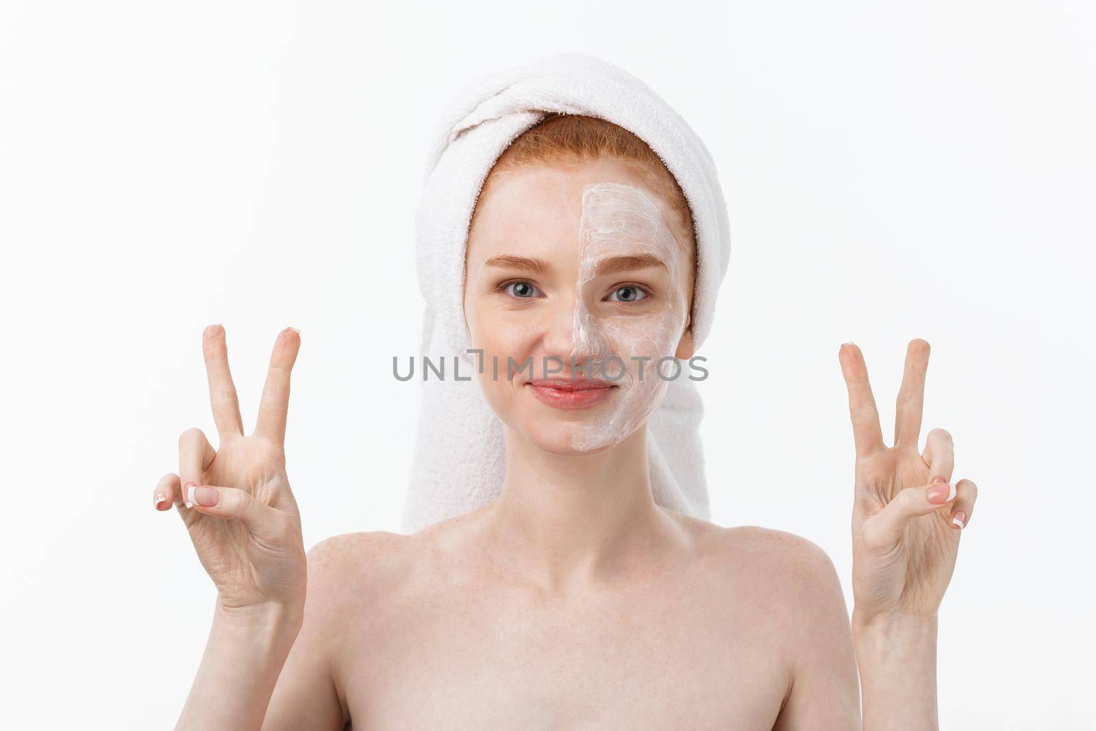 Beautiful caucasian woman applying mask on her face with two fingers sign white background