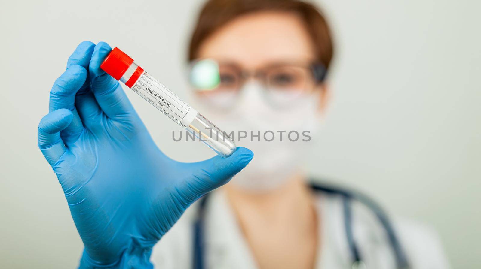 Test for coronavirus Covid-19. Female doctor or nurse doing lab analysis of a nasal swab in a hospital laboratory. Medical technologist holding a COVID-19 smear kit, wearing protective gloves from