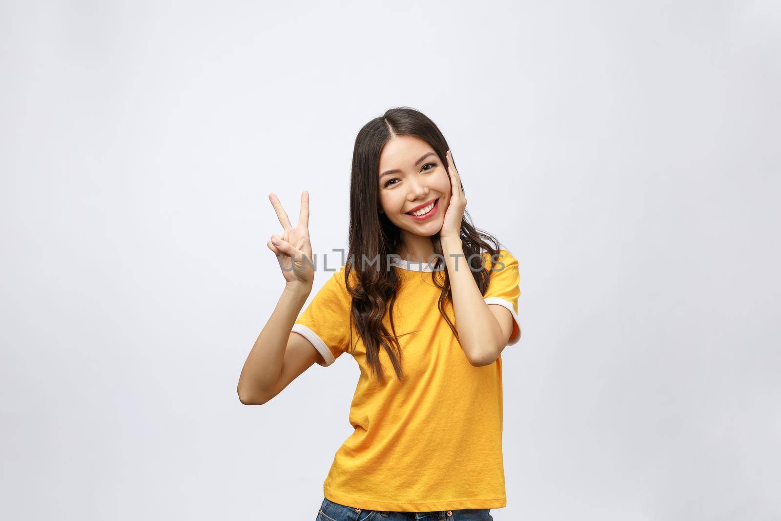 Happy young asian woman showing two fingers or victory gesture with blank copyspace area for text,Portrait of beautiful Asian woman isolated on white background.