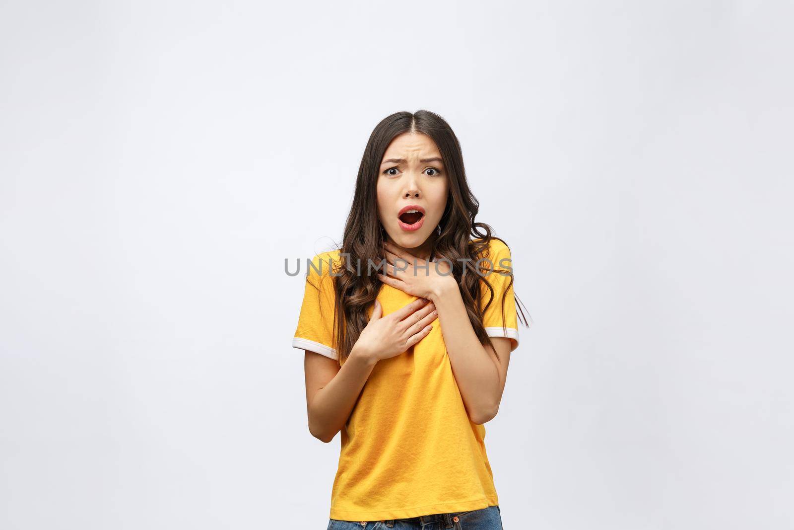 Portrait of nice shocked positive cute young girl in casual yellow shirt, opened mouth, isolated over white background.