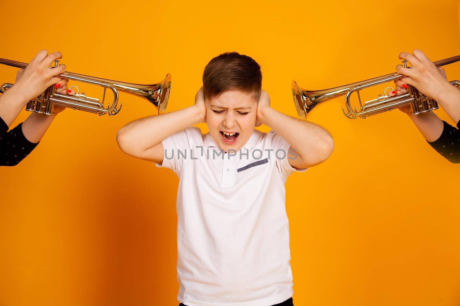 The boy is dissatisfied with the annoyance of a loud sound, he closed his ears with his hands and screams. Loud pipe sound