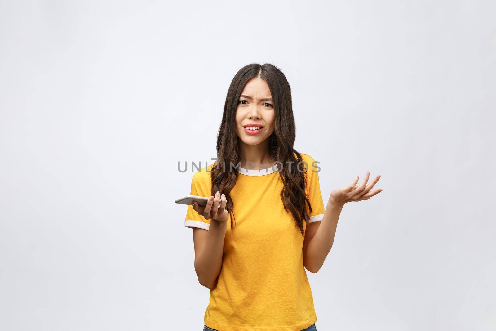 Portrait of a furious asian woman talking on mobile phone isolated over white background by Benzoix