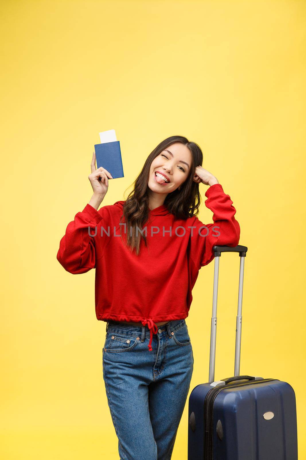 Woman travel. Young beautiful asian woman traveler with suitcase and passport on yellow background.