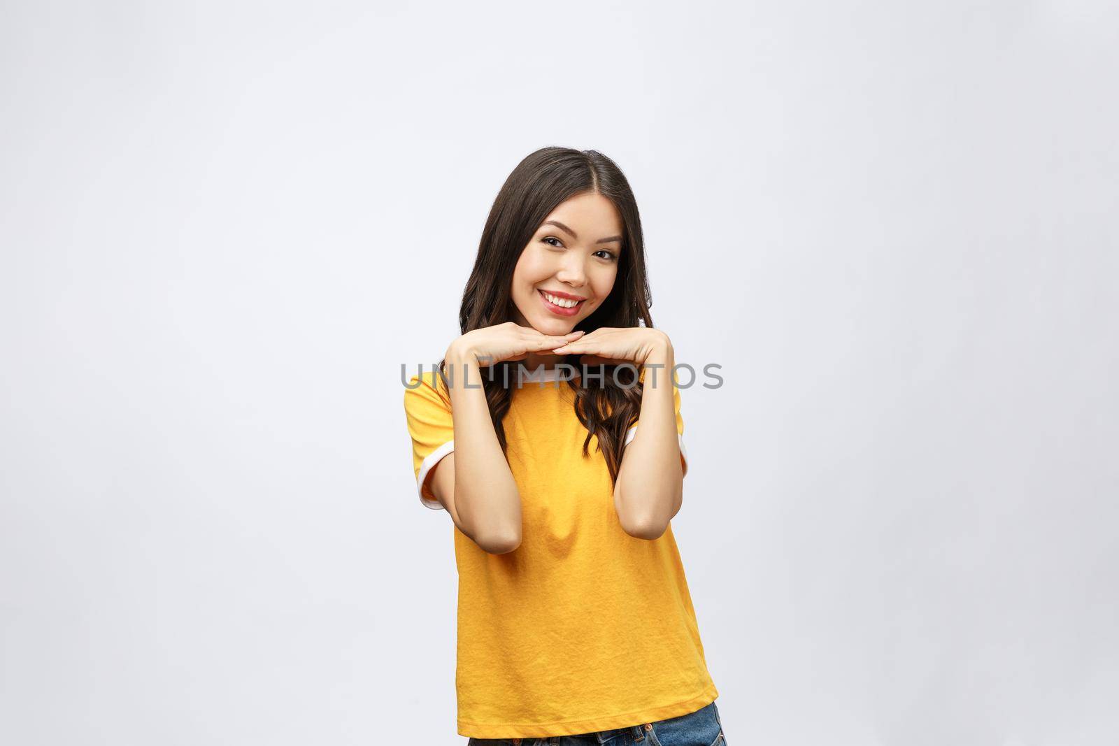 Portrait of good looking woman with long black hair against white background, smiling with hand on chin