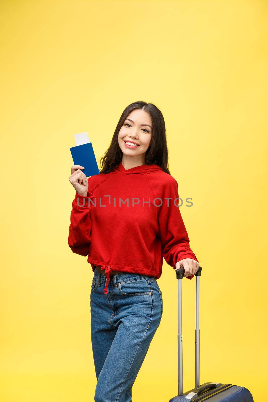 Woman travel. Young beautiful asian woman traveler with suitcase and passport on yellow background by Benzoix