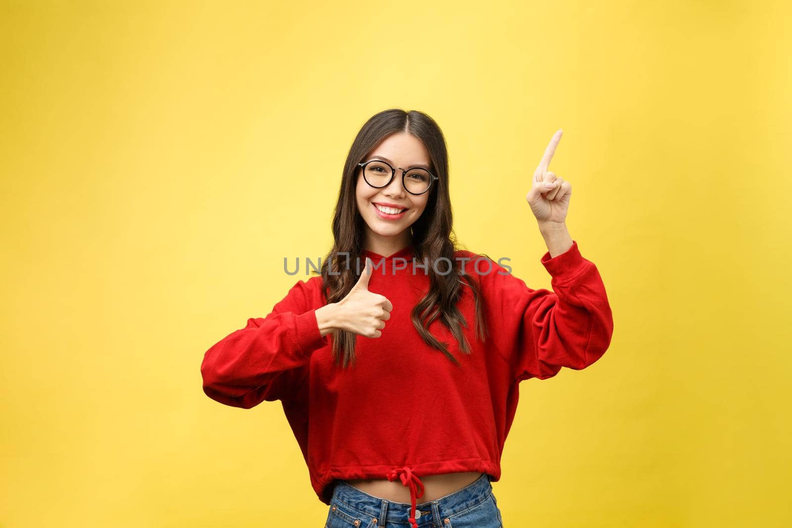 Young beautiful asian woman pointing to copyspace, isolated on yellow background by Benzoix