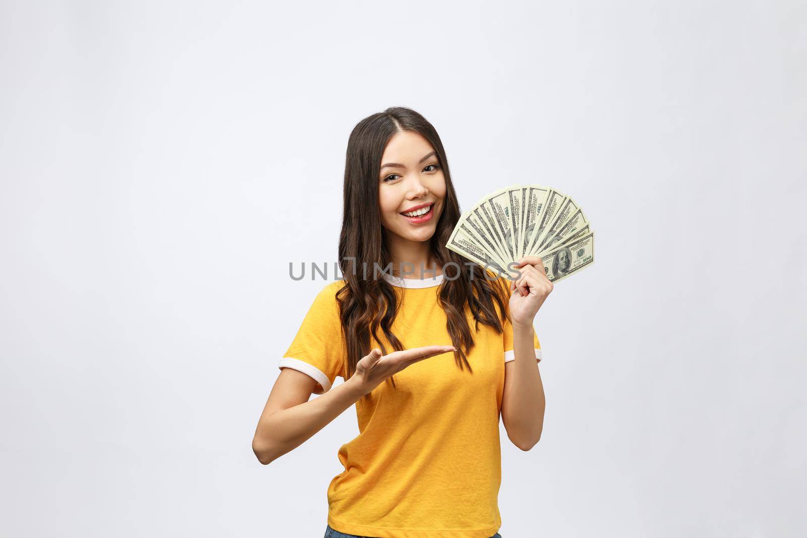 Closeup portrait of beautiful asian woman holding money isolated on white background. Asian girl counting her salary dollar note. Success wealth financial business cashflow currency payment concept.