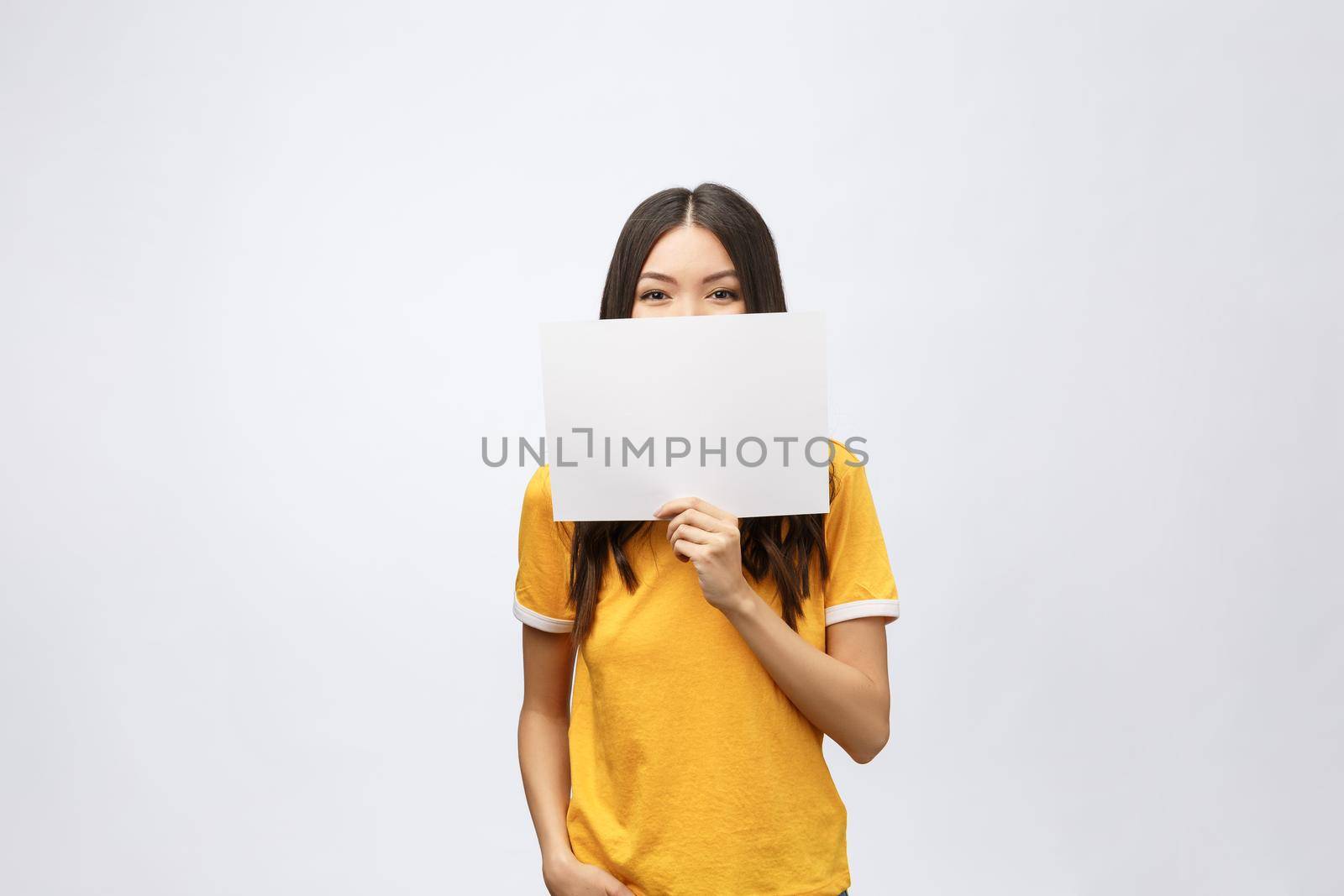 surprised young girl in yellow shirt with white placard in hands isolated.