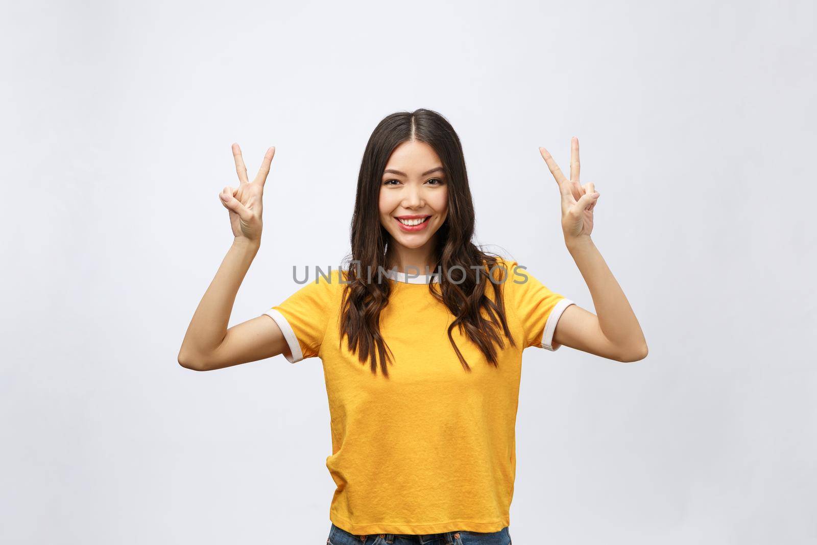 Happy young asian woman showing two fingers or victory gesture with blank copyspace area for text,Portrait of beautiful Asian woman isolated on white background.