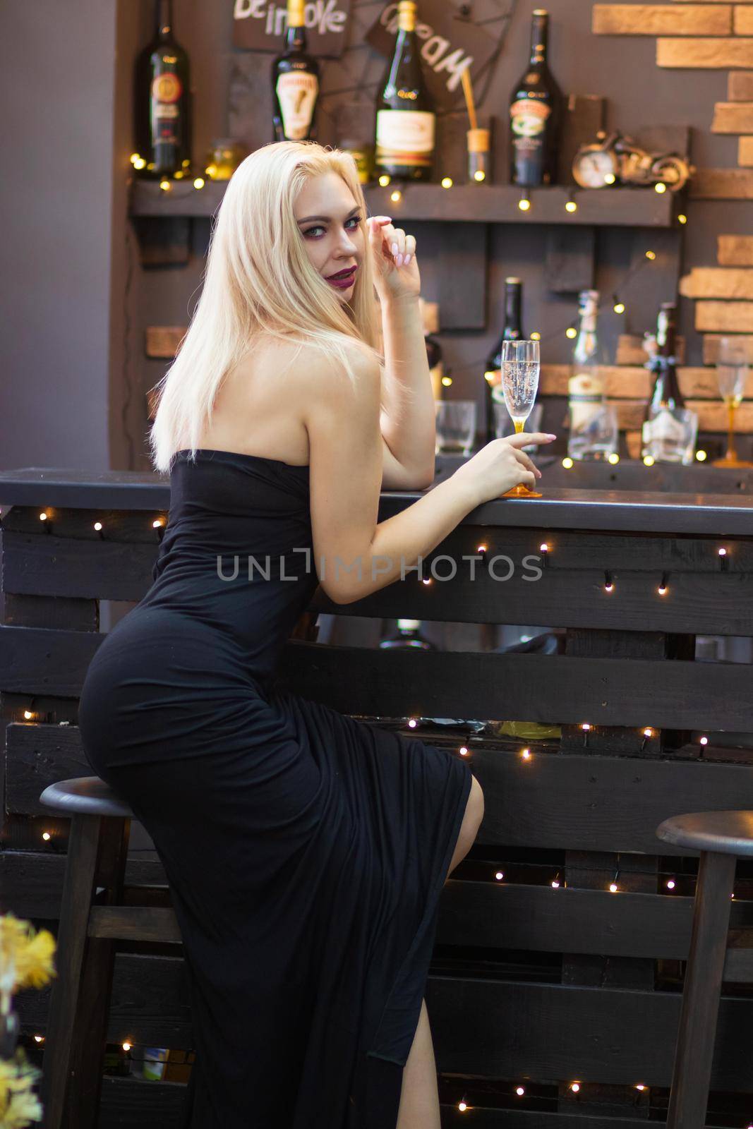 Christmas image with blonde sexy woman in long black dress. Over Christmas decorate and New Year tree