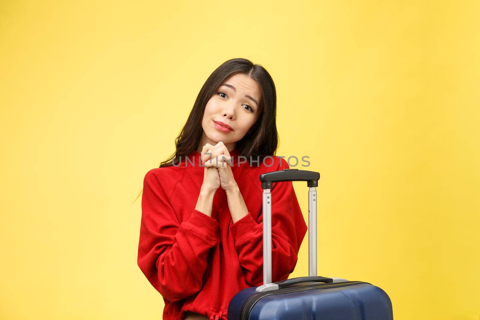 Dream about travel and vacation. Studio portrait of excited pretty young woman with praying hands. Isolated on yellow
