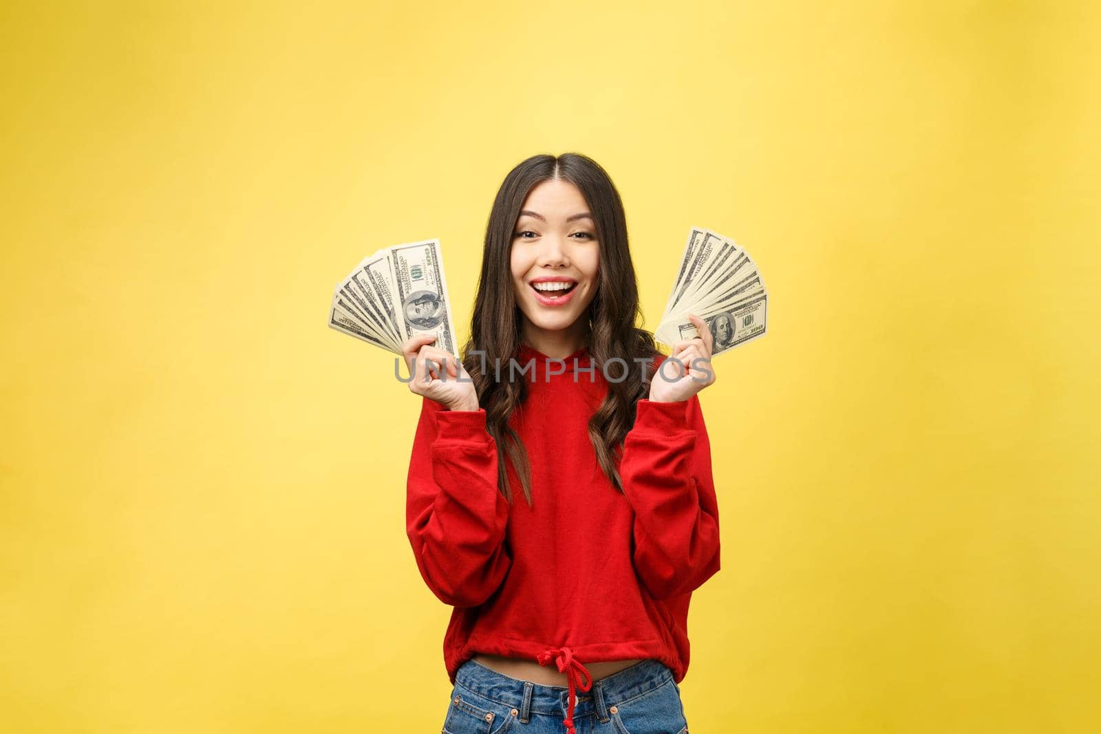 Closeup of young beautiful woman with us dollar money in hand over yellow background, with copy space by Benzoix