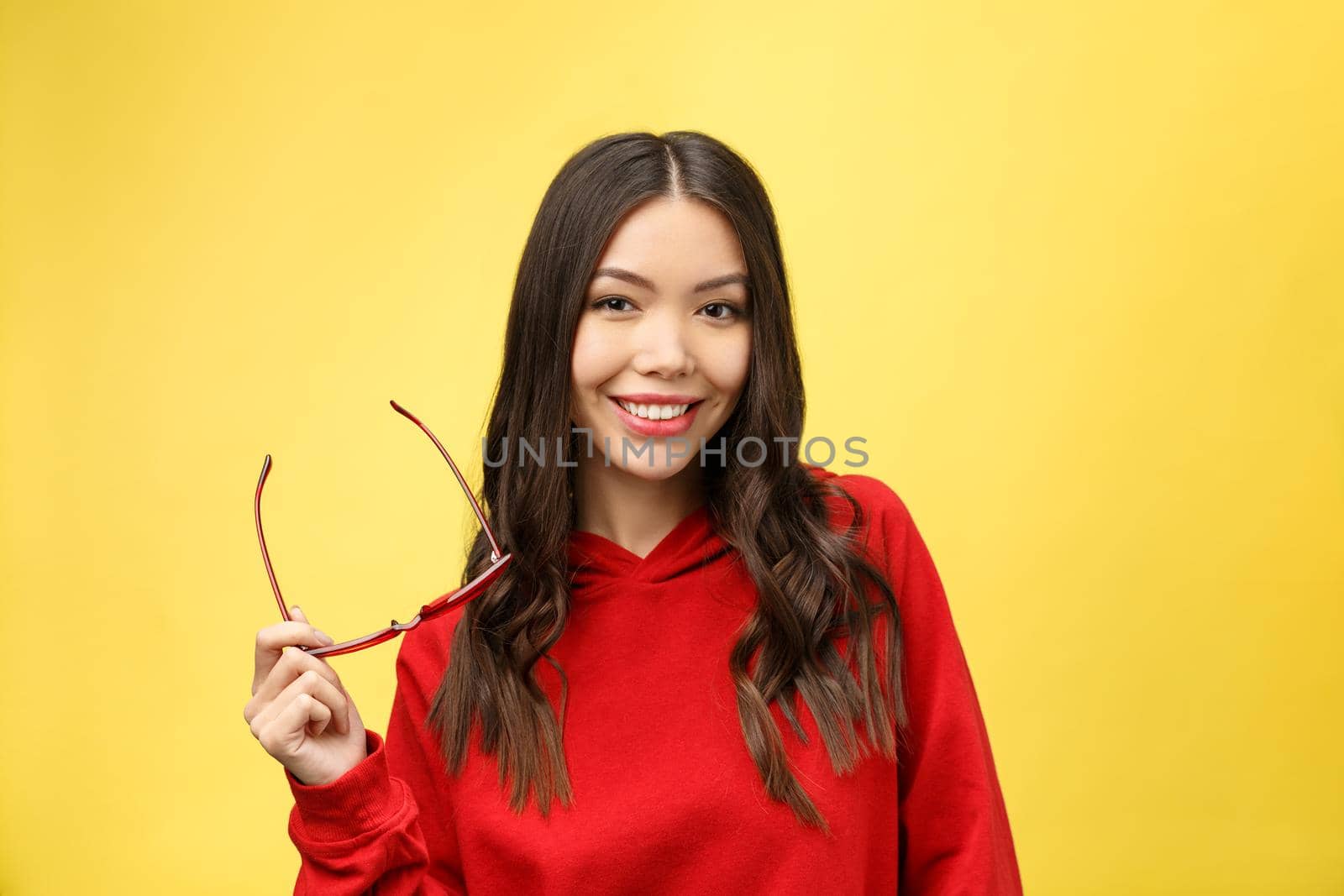 Pretty happy woman in red sunglasses over colorful background.