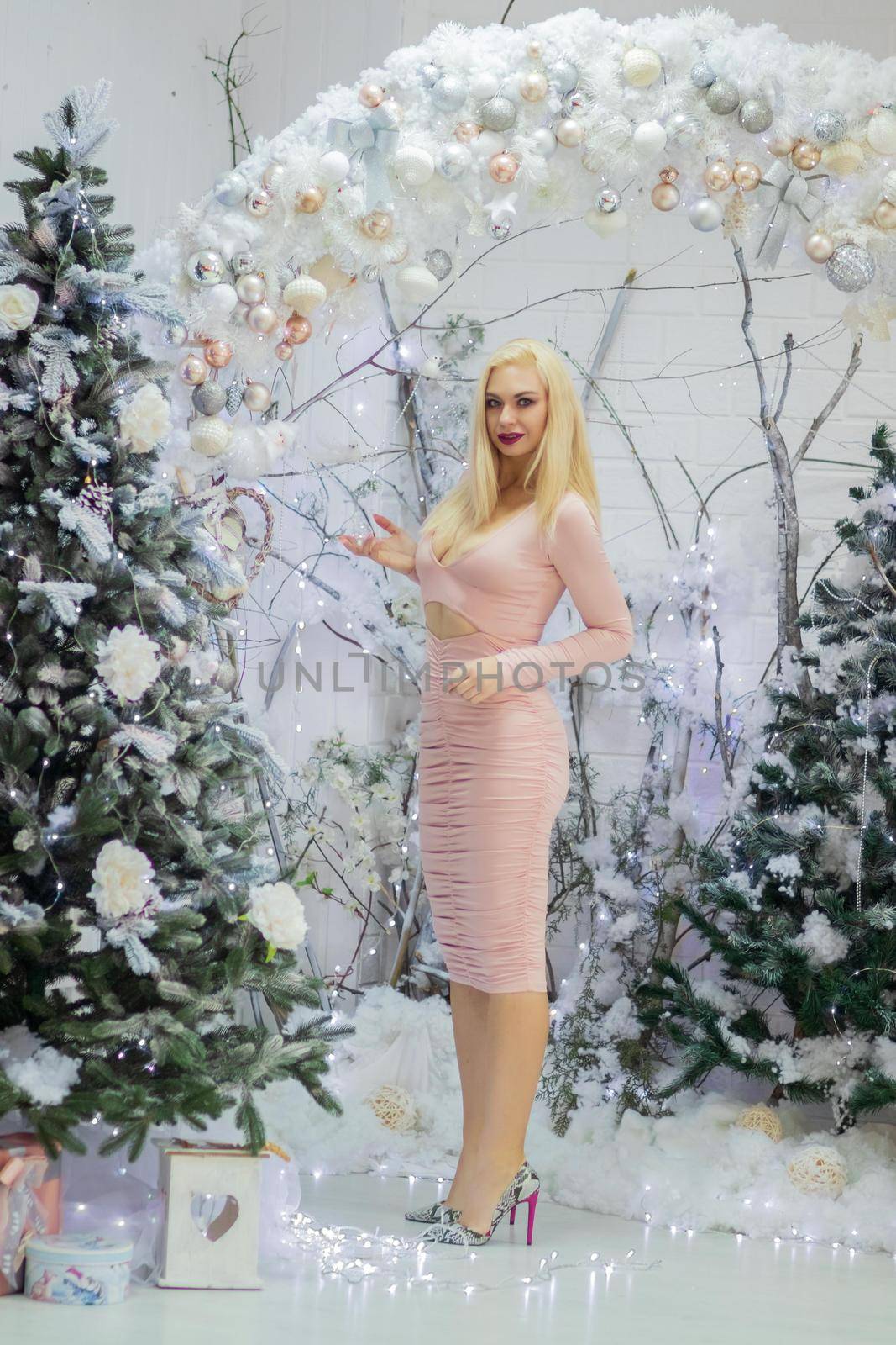 Charming blonde woman in beige sexy dress. Christmas and New Year photo.