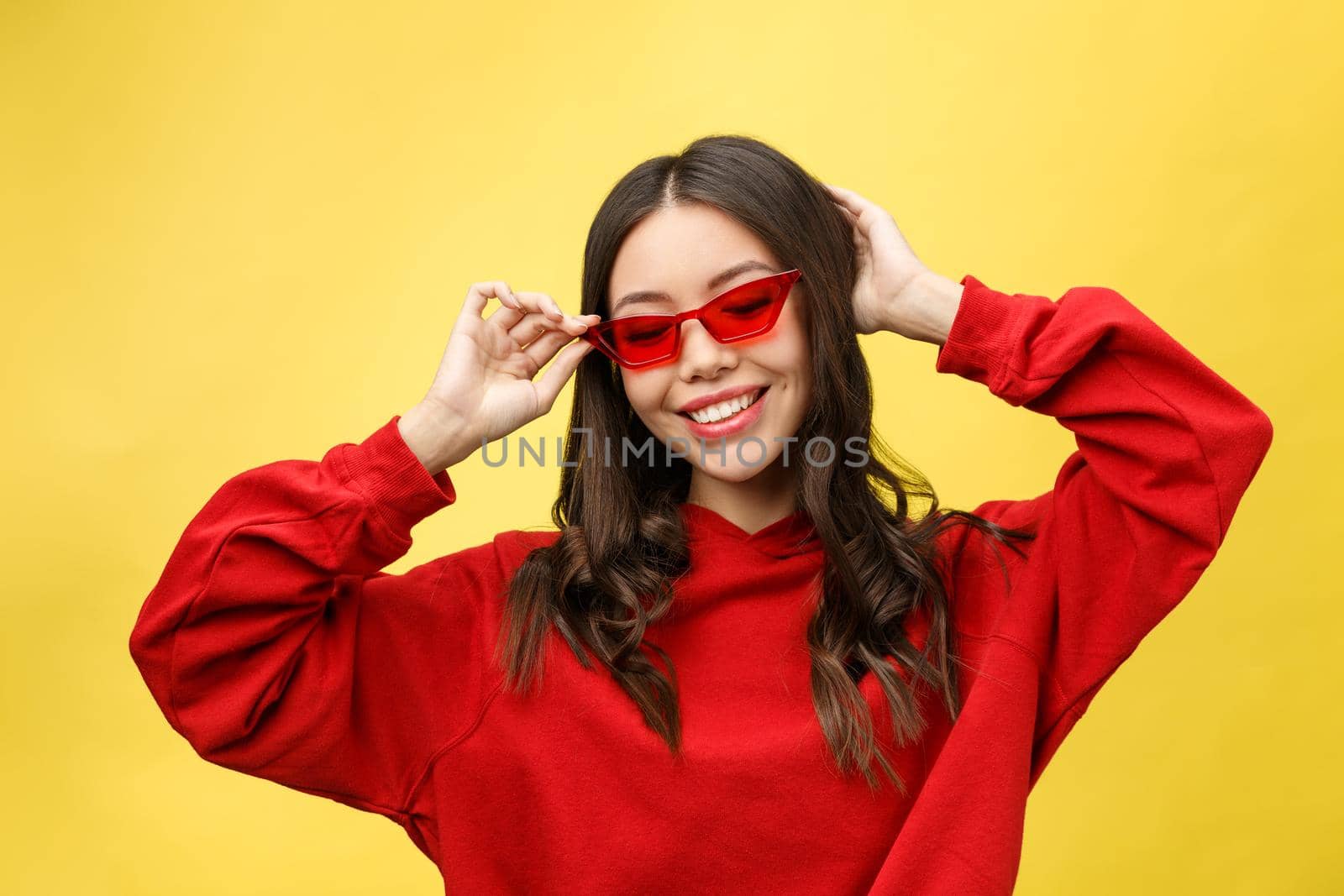 Pretty happy woman in red sunglasses over colorful background.