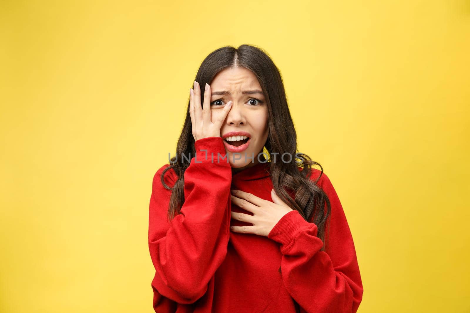 Shocked scared beautiful young woman with mouth widely opened, stares at camera realizes that she disappoint with something, isolated over yellow studio background. by Benzoix