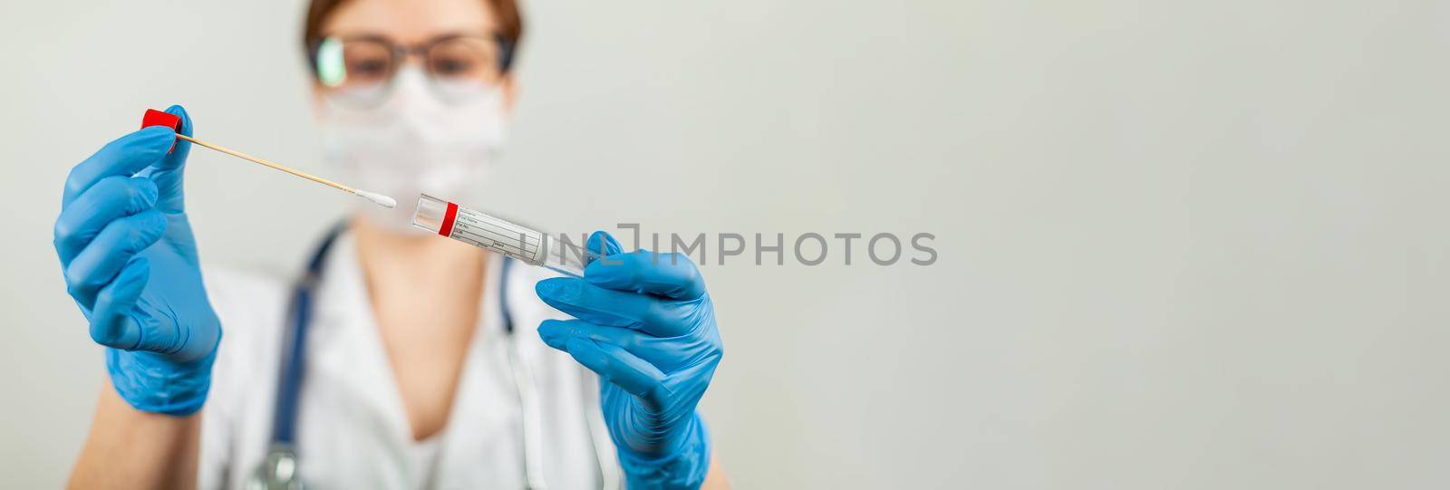 Test for coronavirus Covid-19. Female doctor or nurse doing lab analysis of a nasal swab in a hospital laboratory. Medical technologist holding a COVID-19 smear kit, wearing protective gloves from