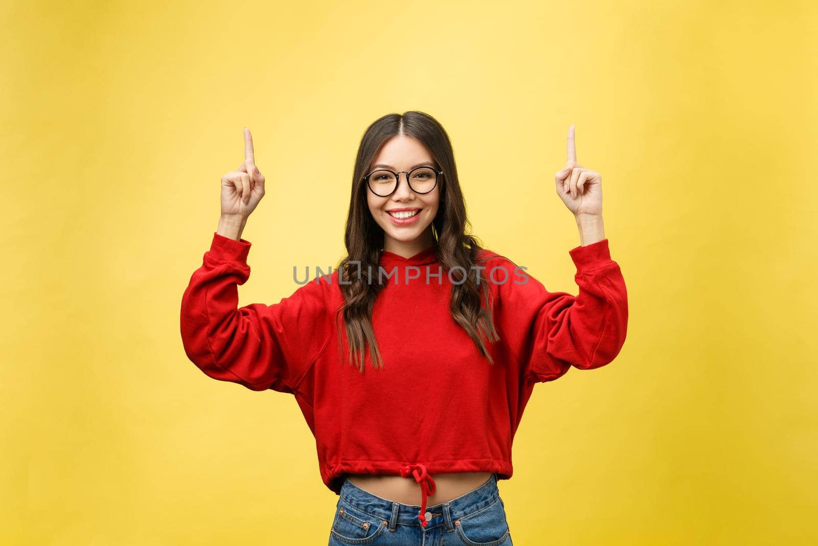 Young beautiful asian woman pointing to copyspace, isolated on yellow background.