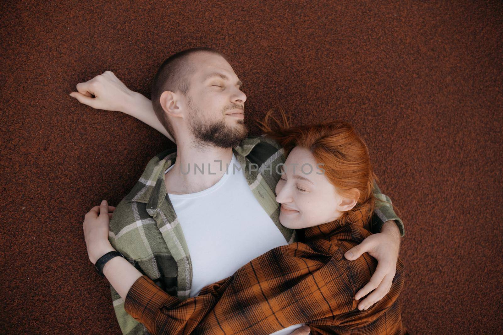 lovers lie on a red covering and hug