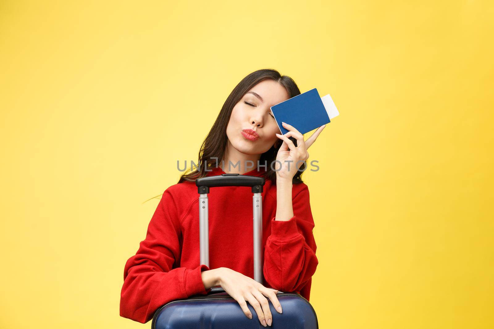 Woman travel. Young beautiful asian woman traveler with passport and suitcase on yellow background by Benzoix