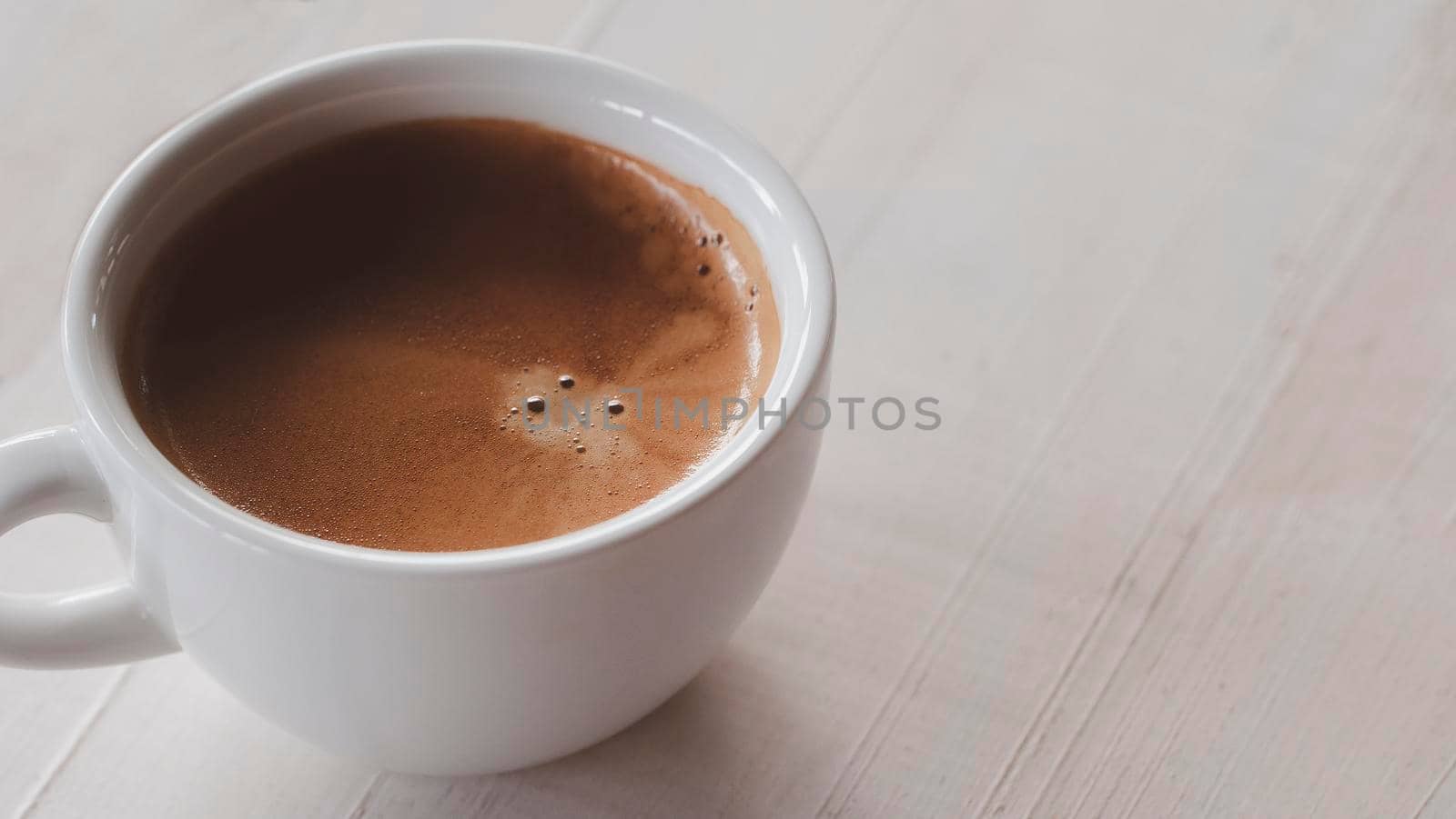 Close up hot cooffee espresso in white cup on white wood table. 