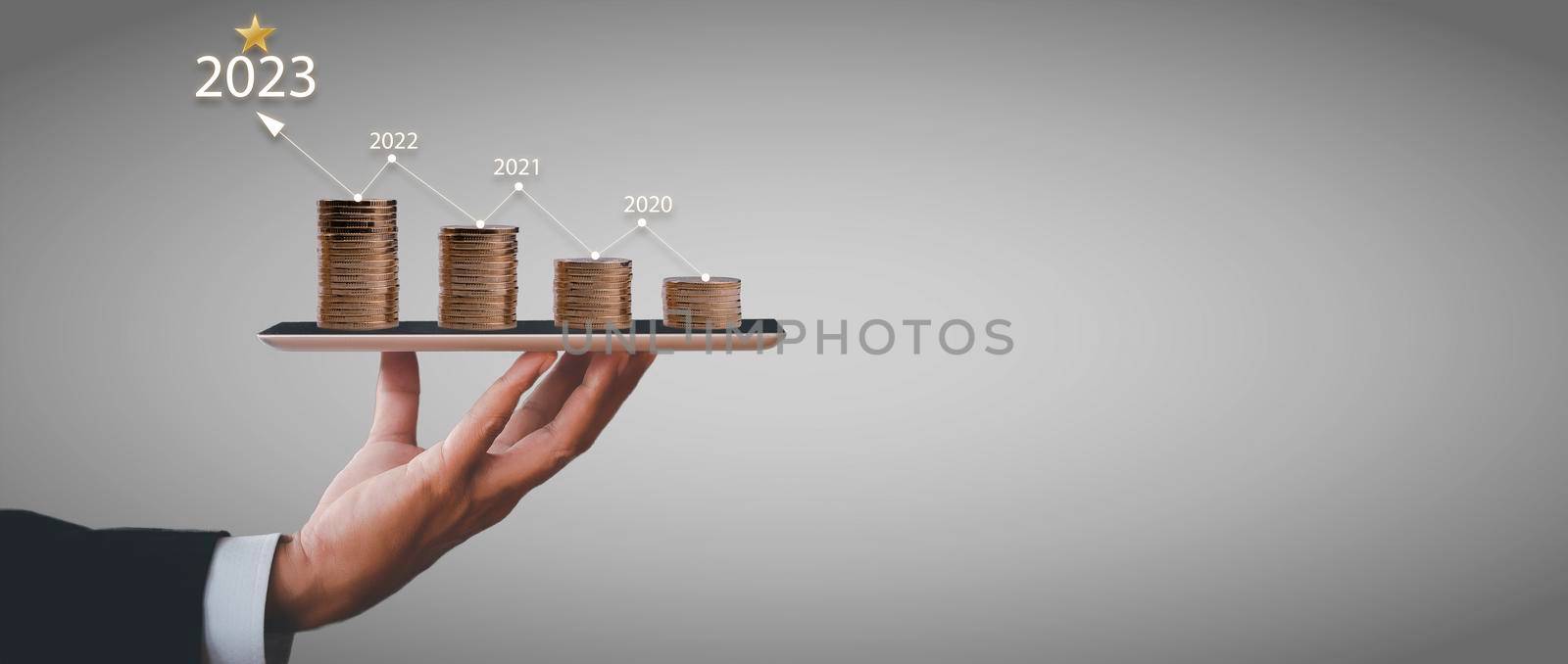 Businessman holding tablet with step coin grows and line arrow with number of year. The idea of maximizing the profit from the business investment.