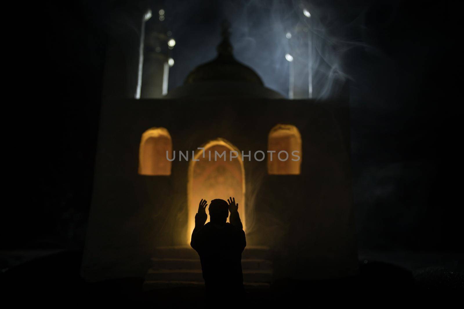 Silhouette of mosque building on toned foggy background. Ramadan Kareem background. Realistic mosque miniature with prayer silhouette. Selective focus