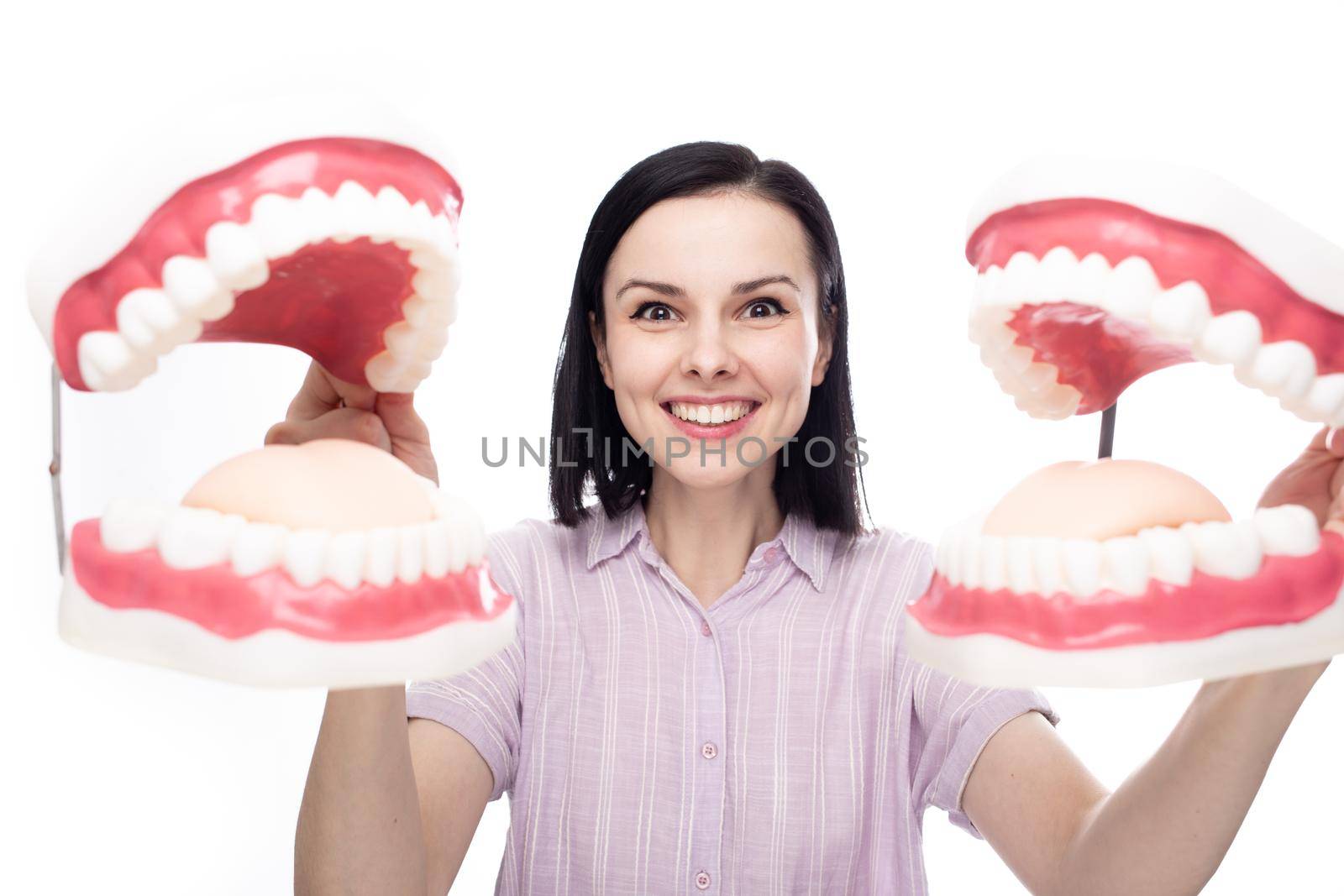 happy woman with perfect smile holding two huge dental jaws in her hands, white background. High quality photo
