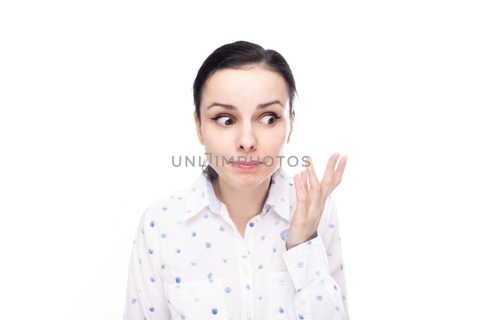 a woman in a white shirt with blue polka dots is unhappy with what is happening, white background. High quality photo