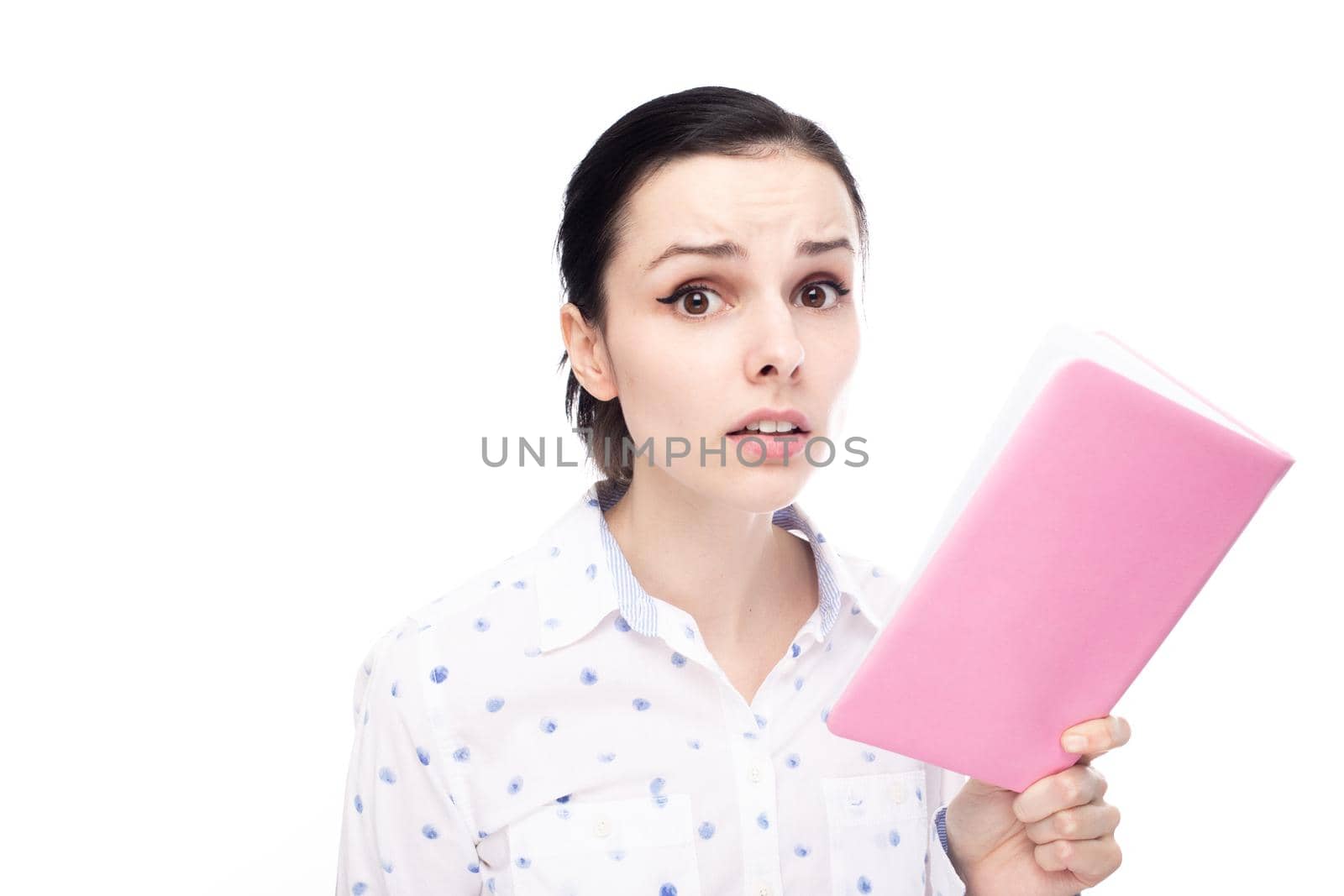 anxious woman in a white shirt holding a pink notebook in her hands, white studio background. High quality photo