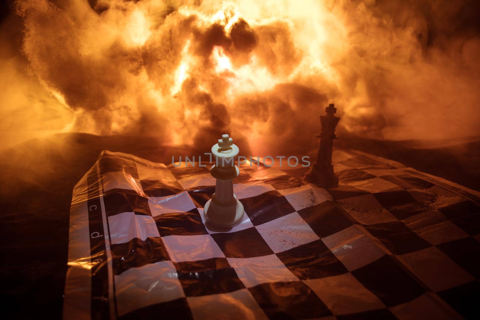 Chess board game concept of business ideas and competition or war theme. Chess figures on a dark background of explosion and fire clouds. Selective focus