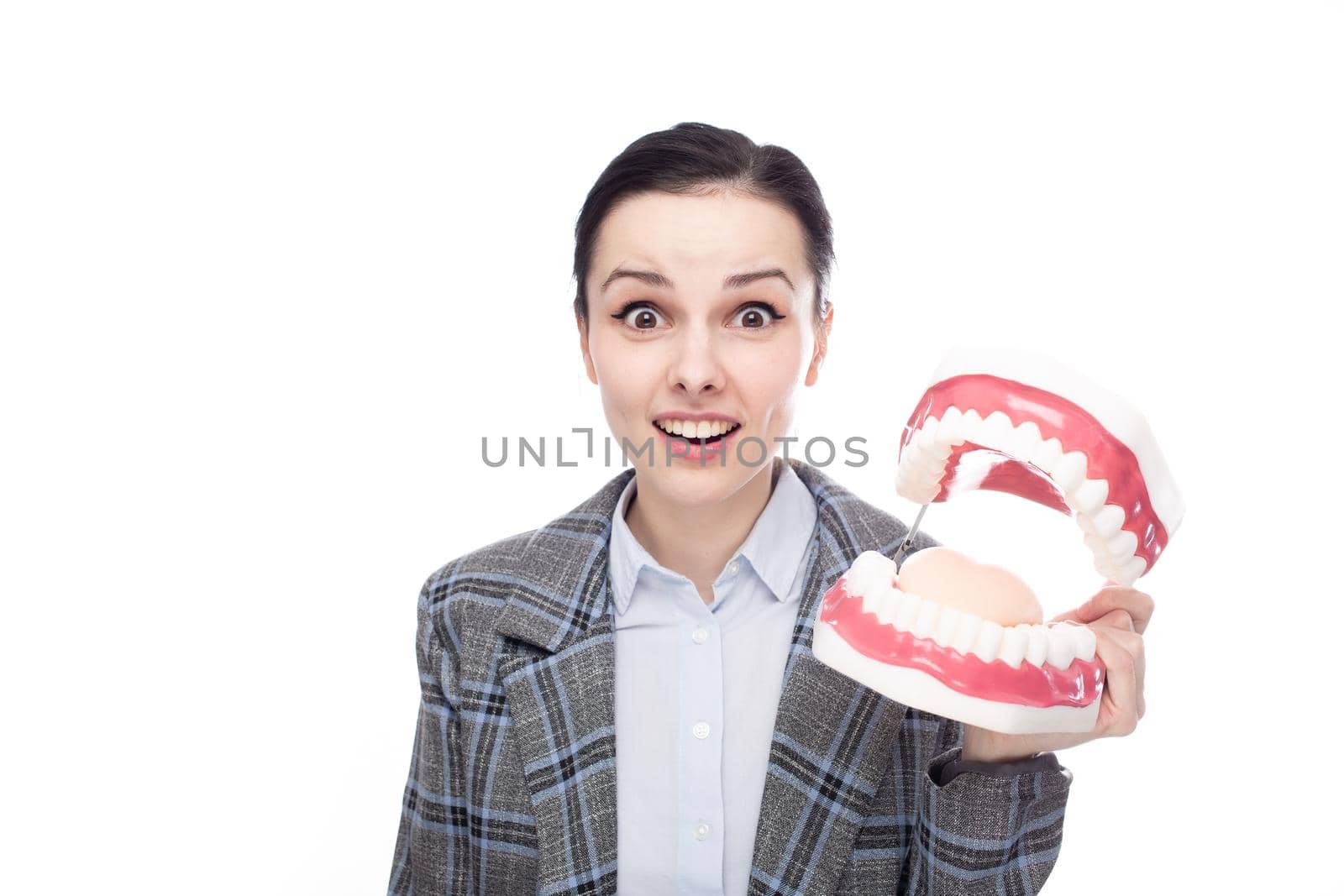 surprised woman in an office suit holds a dental model of the jaw in her hands, white background. High quality photo