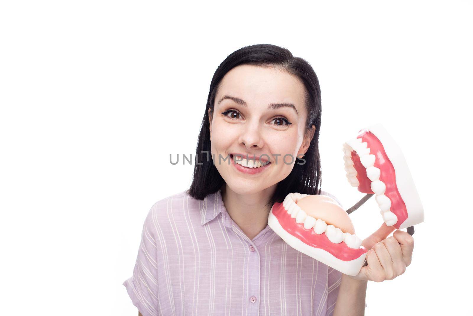 happy woman in purple shirt holding huge jaw mockup in her hand, white background by shilovskaya