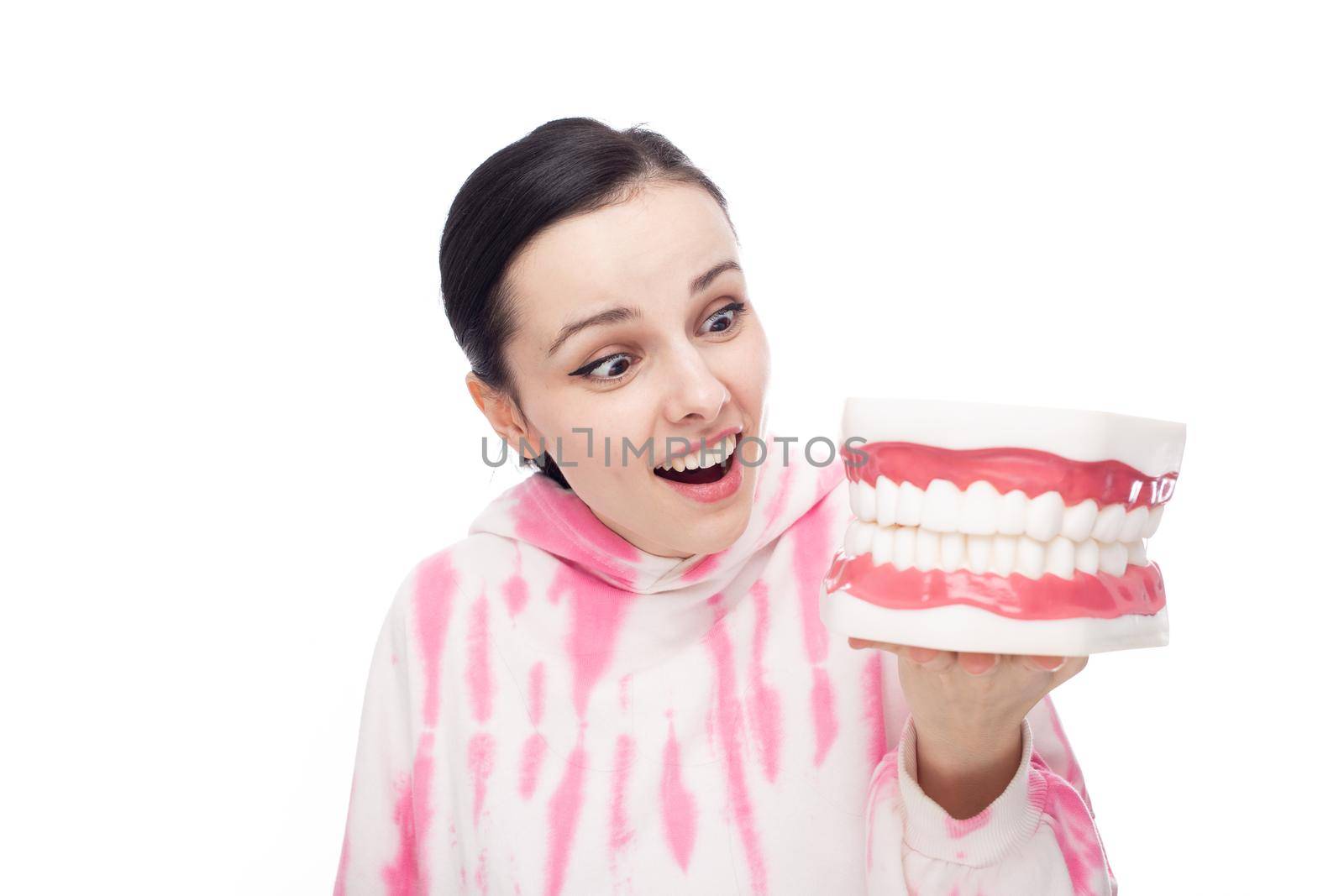 a woman in a pink hoodie looks in surprise at the jaw mock-up, white background. High quality photo
