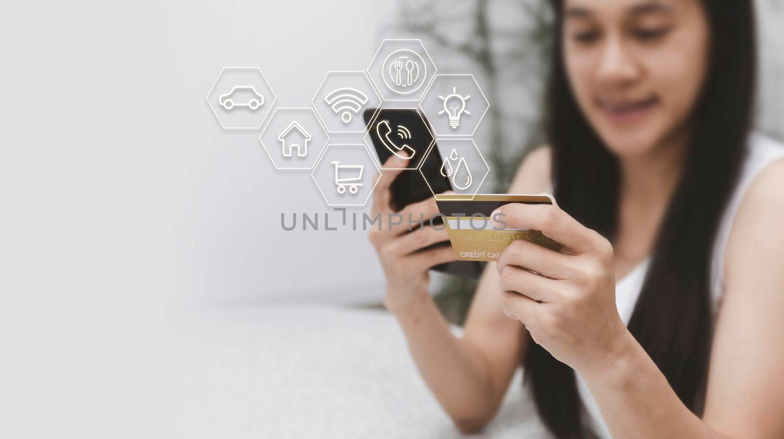 Asian woman holding mobilephone and credit card with various icon concept payment pay for food house, car, water, electricity, telephone bills, online shopping concept. With copy space