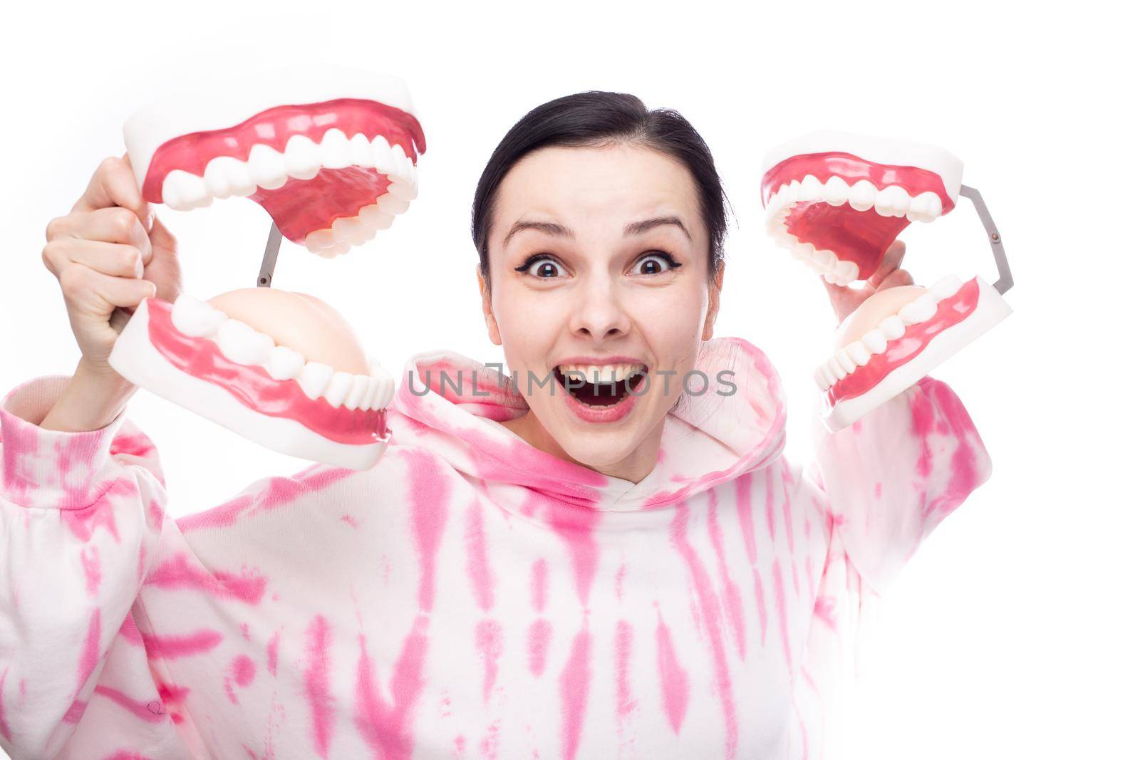 happy woman in pink sweatshirt holding dental mock-ups of the jaw in her hands. High quality photo