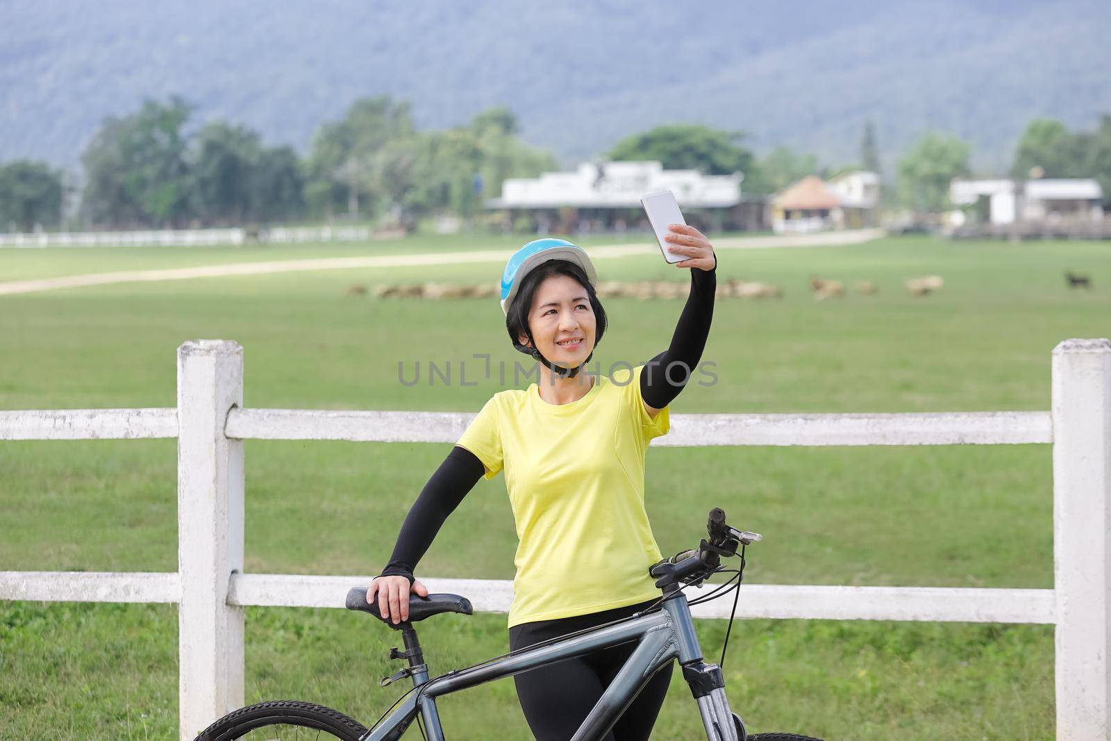 Middle aged women take self photo with phone on her bicycle by toa55